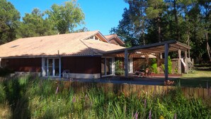 A house with a tiled roof, a covered patio, and a wooden fence.