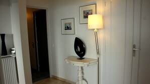 A hallway with a white radiator, a black decorative object on a small table, and a lamp. -  Apartment with Exceptional Panorama (Villefranche sur Mer)