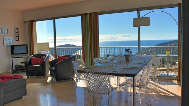 A spacious living area with a large dining table, clear chairs, a sofa, and a TV. -  Apartment with Exceptional Panorama (Villefranche sur Mer)