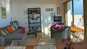 A modern living room with a grey sofa, a black leather armchair, a glass coffee table, and a bookshelf. -  Apartment with Exceptional Panorama (Villefranche sur Mer)