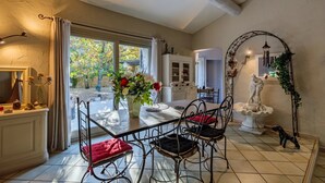 A dining area with a table and chairs, a vase with flowers, and a statue.