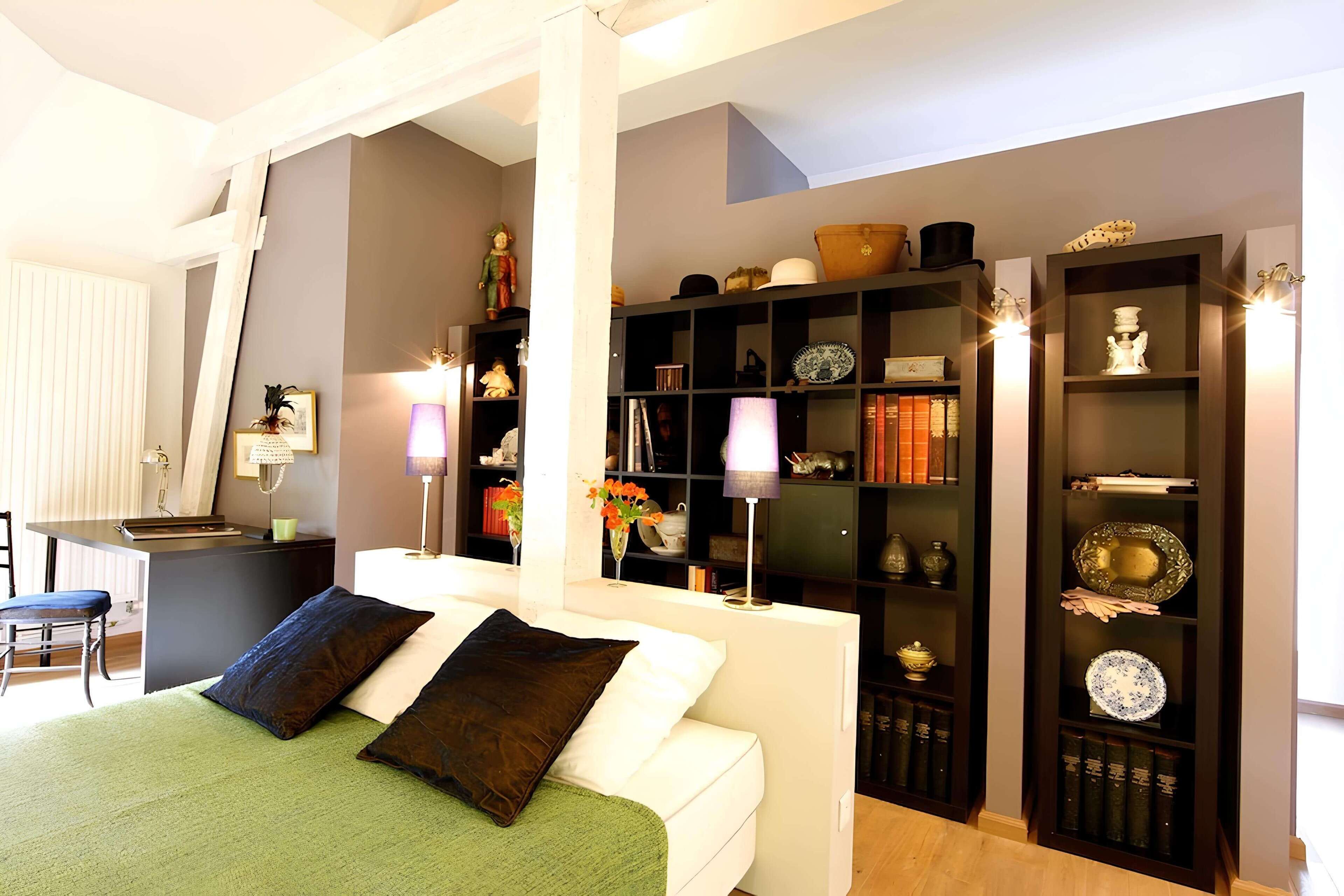 A bedroom with a bed, bedside tables, a desk, and a bookshelf.