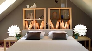 Ein Schlafzimmer mit einem großen Bett, zwei Nachttischen, einem Holz-Kopfteil und einem Dachfenster.