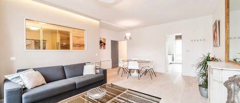Una sala moderna con un sofá gris, una mesa de centro de cristal y una alfombra a rayas.