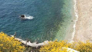 A coastal landscape with clear blue waters, a sandy beach, and a rocky outcrop with buildings. - FRONT DE MER, 50 m² LUXUEUX, 4 Personnes, Beach at 50m, TERRACE of 80m², 3 beds (Carry-Le-Rouet)
