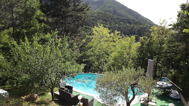 Zona de piscina con vistas a una montaña, rodeada de vegetación exuberante y árboles.