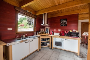 Functional kitchen with a stainless steel sink, microwave, and kettle, offering ample storage and utensils.