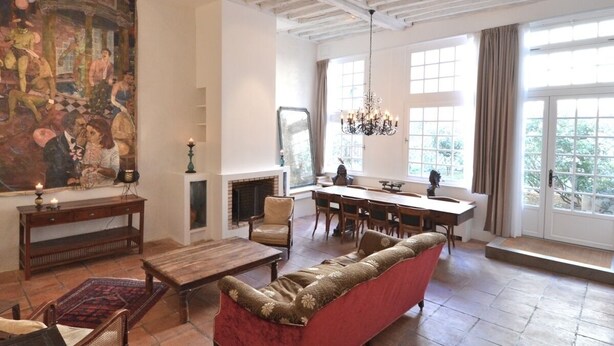 A spacious living room with a fireplace, a dining area, and a large window with curtains.