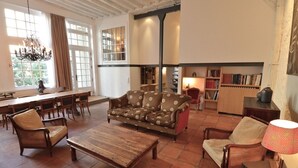 A spacious living room with a sofa, chairs, a coffee table, and a bookshelf.