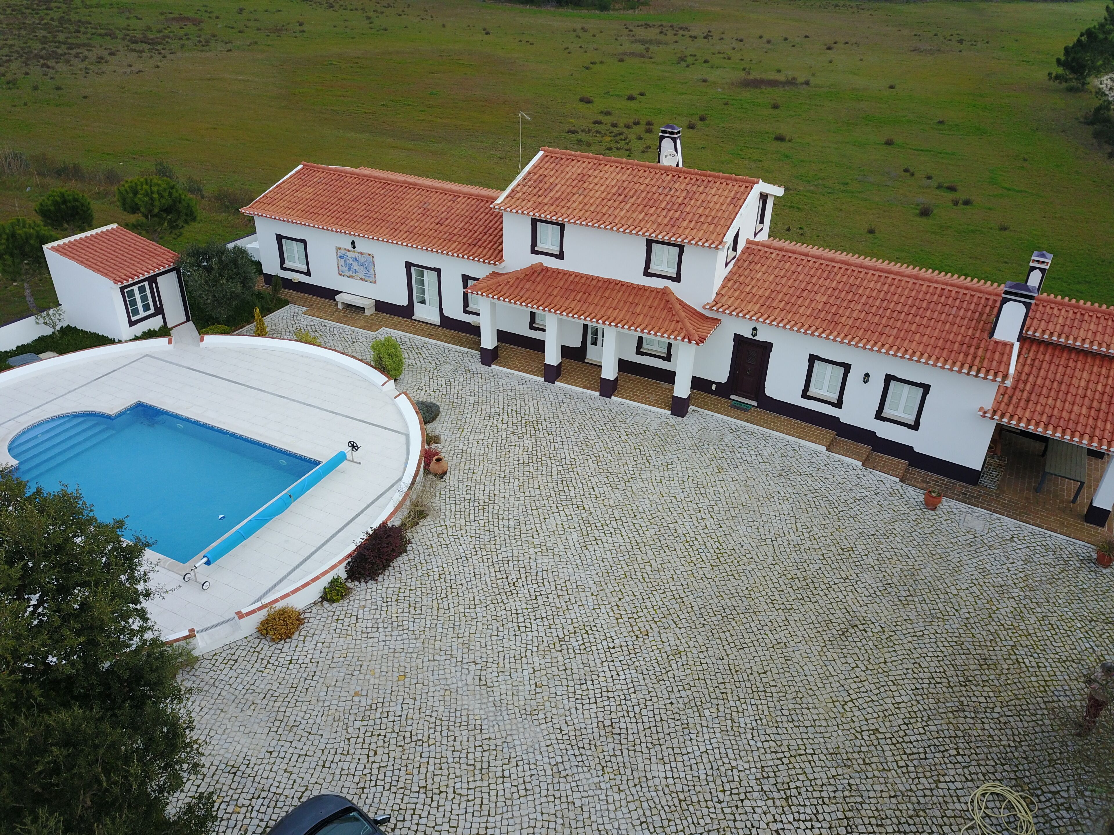 A large house with a swimming pool and a paved courtyard.