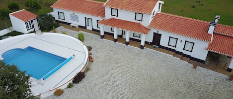 A large house with a swimming pool and a paved courtyard.