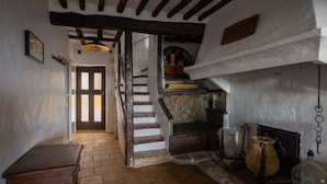 Interior rústico com escada de madeira, uma pequena mesa e luminária pendente.
