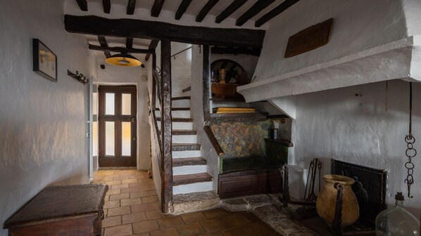 A rustic interior with a wooden staircase, a small table, and a hanging light fixture. - House of character in the heart of a medieval village, Tourrettes sur Loup (Tourrettes-Sur-Loup)