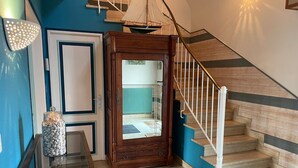 A staircase with wooden steps and white railings, a glass table with a jar of items, and a door with a mirror. - Bright and comfortable house in a quiet area in a wooded park near the beaches. (Plouharnel)