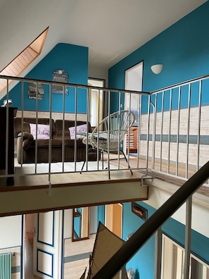 Un espacio habitable en varios niveles, con una escalera, un conjunto de sofás y una silla.