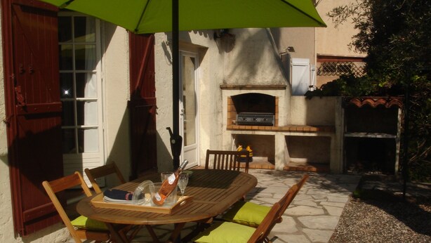 An outdoor patio with a wooden table and chairs, a green umbrella, and a brick oven. - Townhouse ,, 3 + 1 bedrooms, 2. 5 bathrooms, air conditioning, wifi PRICE REDUCED (Fréjus)