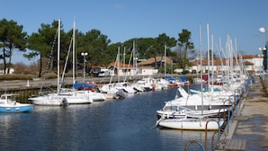 A marina with various boats docked, a wooden walkway along the water, and houses in the background. - HOUSE WITH HEATED SWIMMING POOL 50 M FROM ANDERNOS BEACH (Andernos-Les-Bains)