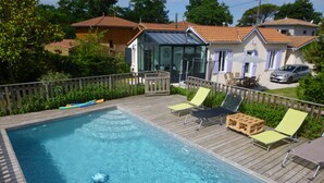 A swimming pool with wooden deck and lounge chairs. - HOUSE WITH HEATED SWIMMING POOL 50 M FROM ANDERNOS BEACH (Andernos-Les-Bains)