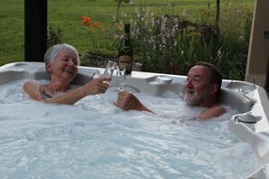 A hot tub with two people toasting with champagne glasses. - Gîte with SPA in a large park in the heart of Périgord ( Monpazier-Dordogne) (Capdrot)