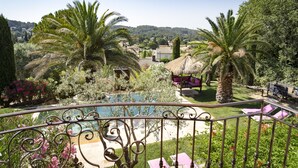 A balcony with a pool, surrounded by palm trees and a garden.
