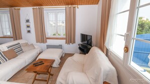 Un soggiorno accogliente con soffitto in legno, tende beige, televisione e divano.