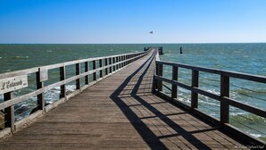 Una banchina in legno che si protende verso il mare, con un cartello che riporta la scritta 'L'Estuaire'.