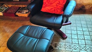 A black leather office chair with a red cushion in a rustic room with a stone wall and a window. - "Charming troglodyte house near Sarlat (Vitrac)