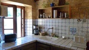 A kitchen with a tiled backsplash, wooden cabinets, a coffee maker, and a sink with a faucet. - "Charming troglodyte house near Sarlat (Vitrac)