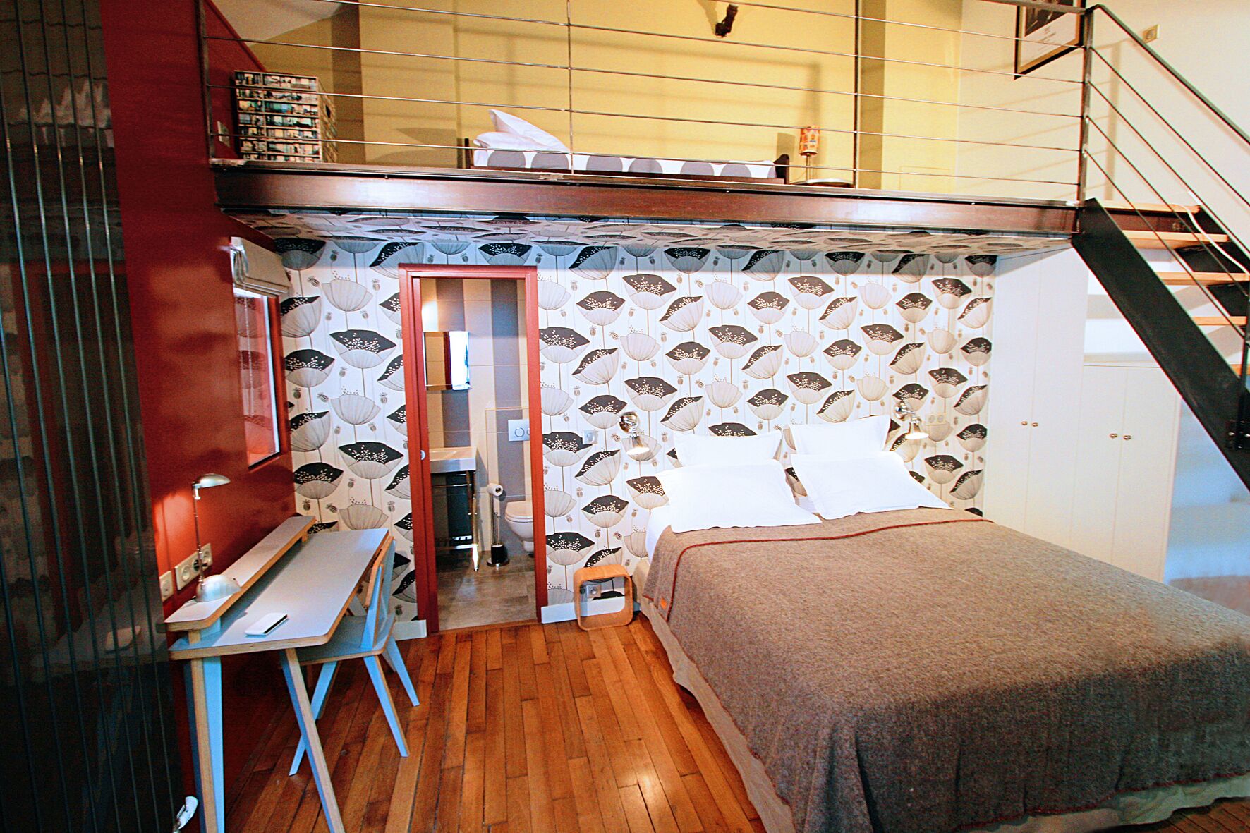 A compact bedroom with a bunk bed, a small desk, and a bathroom.