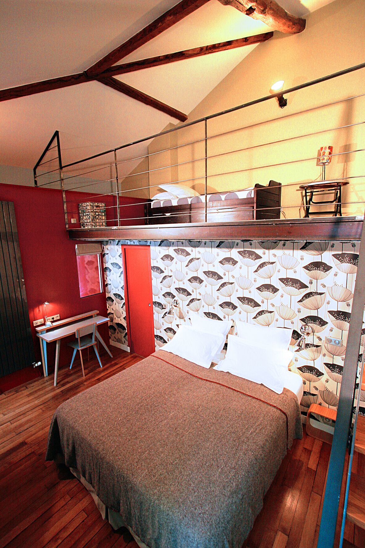 A compact bedroom with a bunk bed, a desk, and a patterned wallpaper.