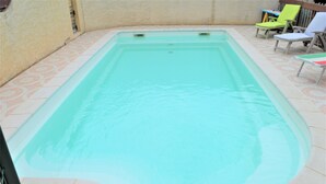 A rectangular swimming pool with a tiled edge, surrounded by a patio area with chairs. - Luxury 200m² villa with private pool, Clevacances label (3 keys) (Saint-Clément)