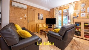 A living room with leather sofas, a wooden coffee table, a flat-screen TV, and a wooden cabinet with kitchenware. - Luxury 200m² villa with private pool, Clevacances label (3 keys) (Saint-Clément)