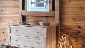 A wooden-paneled room with a bed, a small window with a blind, a wicker basket on a dresser, and a woven floor lamp. - SEASONAL RENTAL VILLA STANDING 3/4 PERS (2 ADULT / 2 NFE). POOL SPA SAUNA (Le Moule)