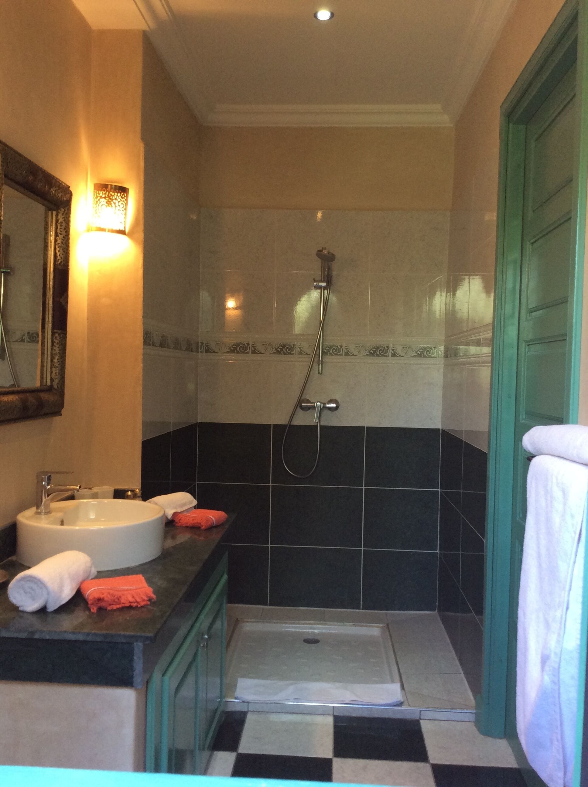 Une salle de bain équipée d’un lavabo, d’un miroir, d’un porte-serviettes, d’une douche et de murs carrelés.