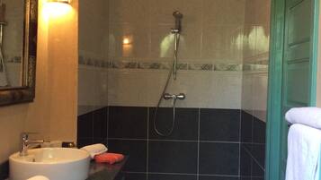 Une salle de bain équipée d’un lavabo, d’un miroir, d’un porte-serviettes, d’une douche et de murs carrelés.