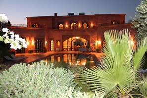 A large building with a pool, outdoor seating, and a well-lit entrance.