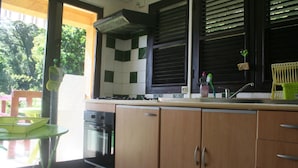 A kitchen with wooden cabinets, a sink, and a window with blinds. - between the sea and the Caribbean sun garden (Trinité)
