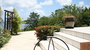 A stone pathway leading to a set of steps with a large pot on the right. - between the sea and the Caribbean sun garden (Trinité)