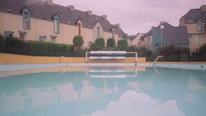 A swimming pool with a bench in the middle, surrounded by residential buildings.