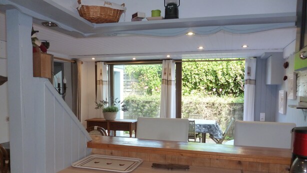 A kitchen with a wooden countertop, a sink, and a window overlooking a garden.