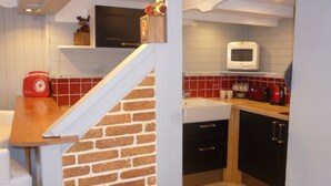 A kitchen with a brick wall, wooden counter, and a microwave.