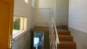 A staircase with metal railings, wooden steps, and a view of the outdoors through a window.