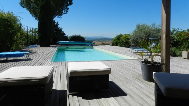 Eine Holzterrasse mit Pool, Liegestühlen und Blick auf die Landschaft.