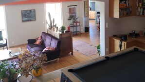 Ein großzügiger Wohnbereich mit Billardtisch, einer Couch und einem Bücherregal.