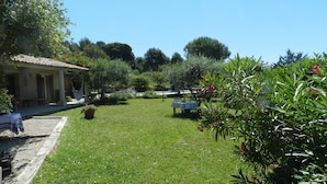 Ein Garten mit einer Terrassenfläche, einem Tisch und Stühlen.