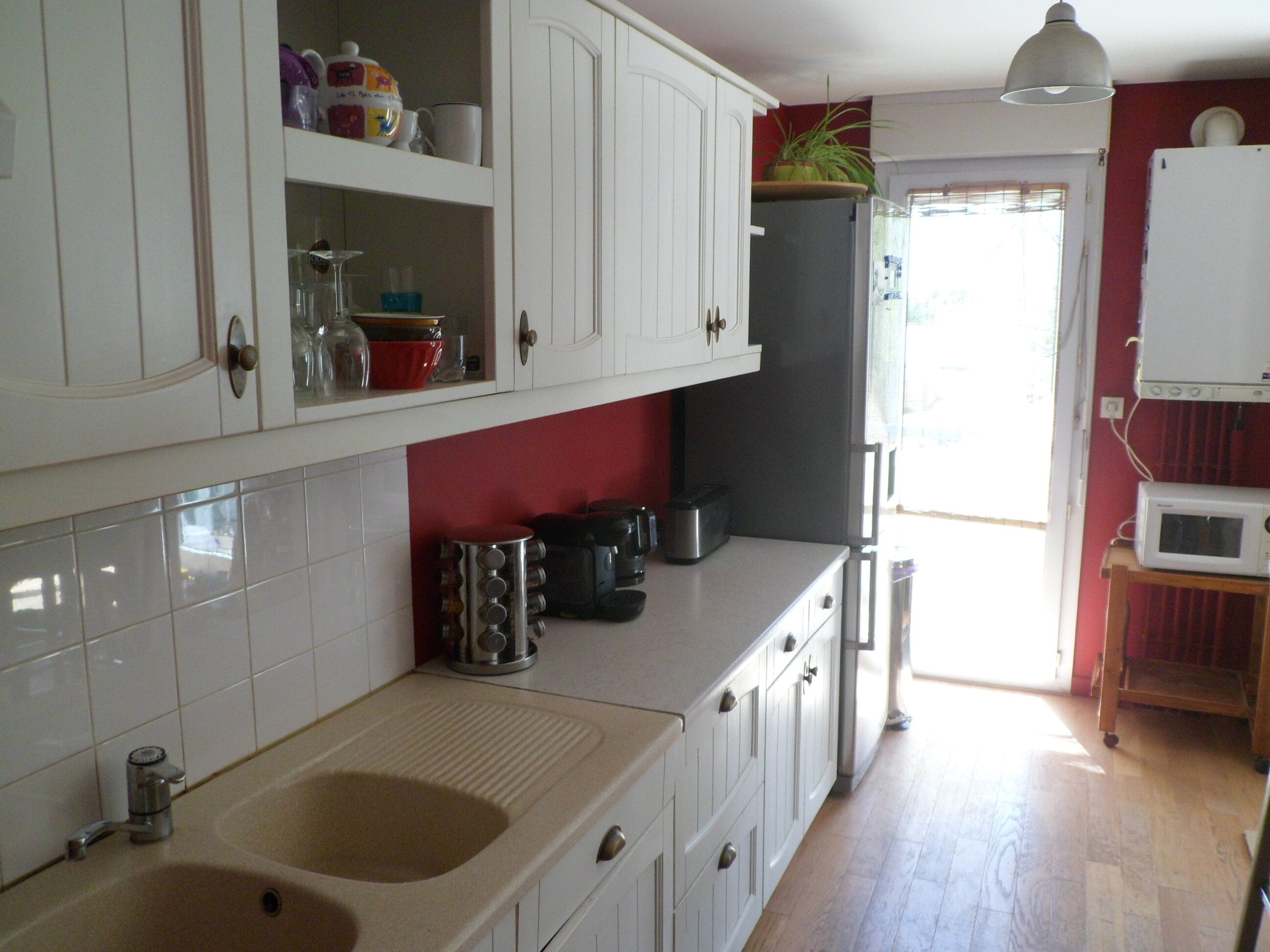 A kitchen with white cabinets, a sink, and a microwave on a wooden table.
