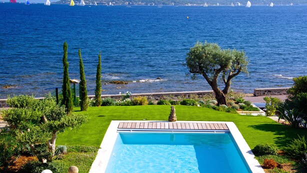 En pool med udsigt til havet og sejlbåde.