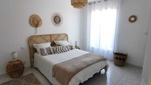 Une chambre à coucher avec un lit, une fenêtre avec des rideaux et des éléments de décoration murale.