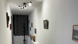 Ein Flur mit weißen Wänden, einem Heizkörper und einer Treppe, die zu einer oberen Etage führt.