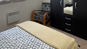 Ein Schlafzimmer mit einem Bett, einem Schrank, einem Sessel und einem Fenster.